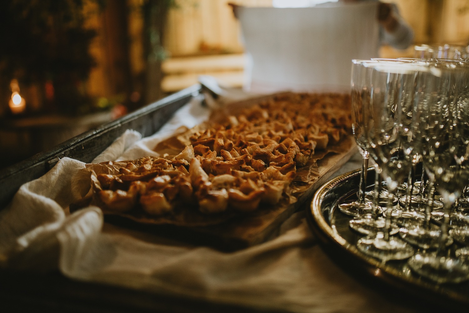 Nybakade smördegspiroger på en plåt bredvid ett stativ med champagneglas.