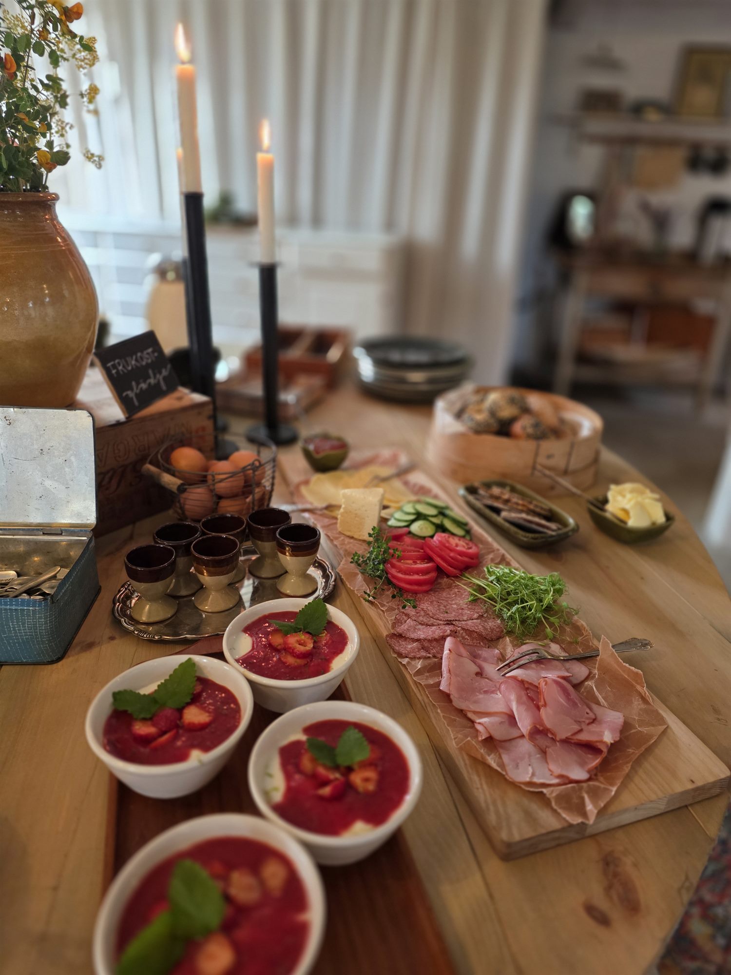 Dukat frukostbord med ljus, ägg, charkbricka och bär, redo för morgonen efter.
