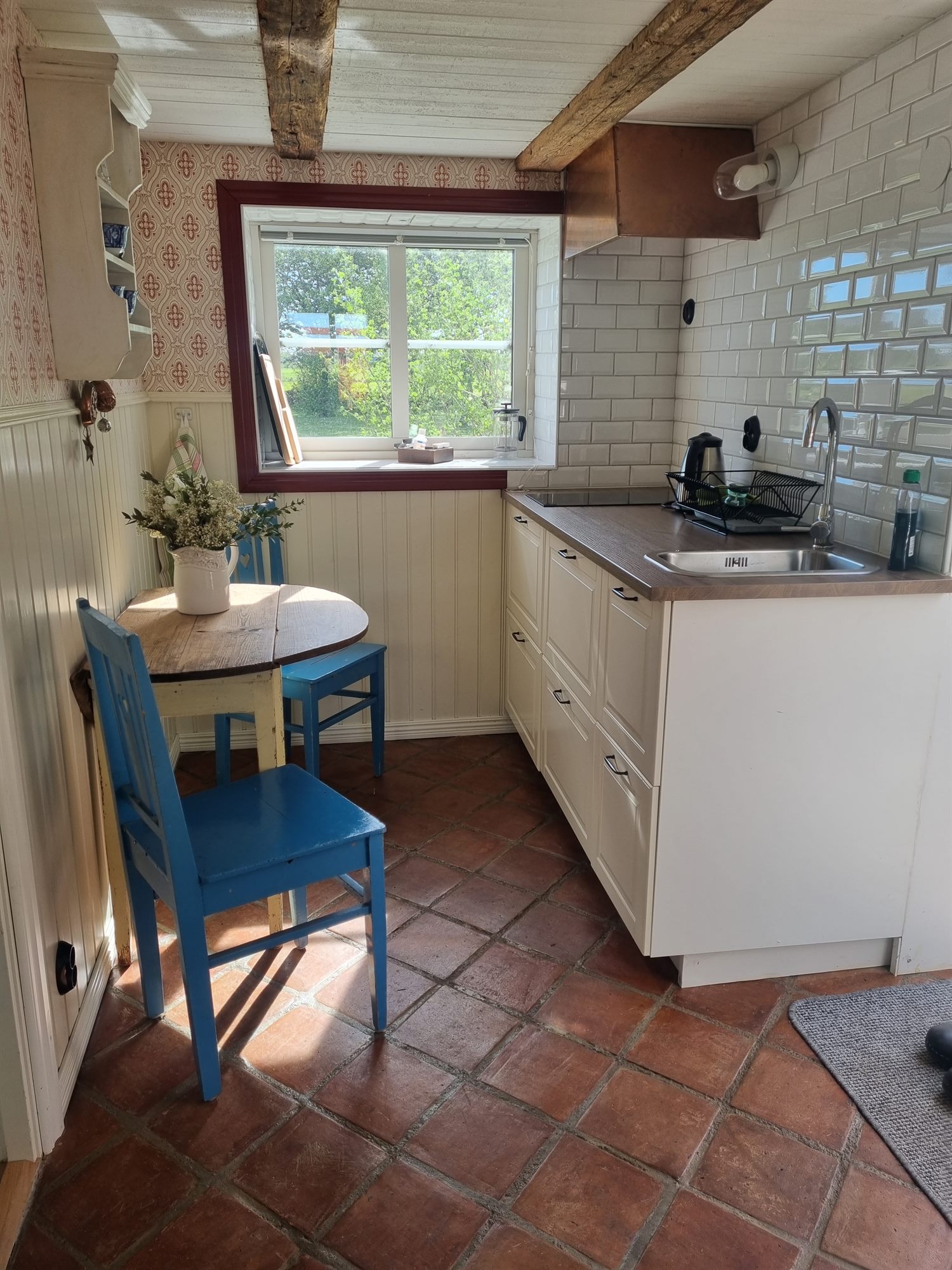 Pentry i Gårdshuset med köksbord, blå stolar och terrakottagolv.