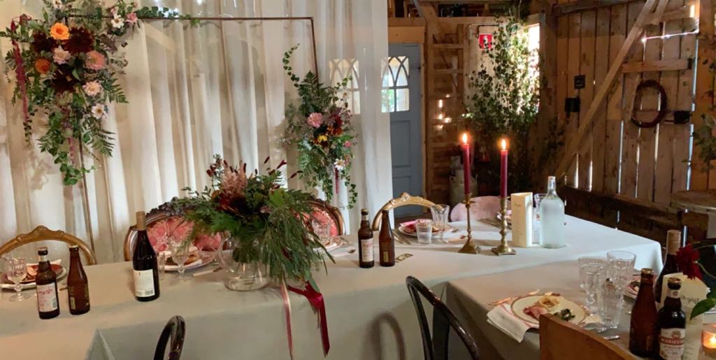 Dukat bord för fest i ladan i Rönnås Lada, med höga ljus, blomsterarrangemang och vita dukar.
